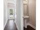 Hallway leading to a powder room with pedestal sink, mirror, and hardwood flooring at 3102-A Brownstone Se Ln, Atlanta, GA 30354