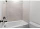 White bathtub with tile surround and dark fixtures in a well-lit bathroom at 7675 Homer Dr, Cumming, GA 30028
