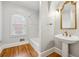 Bright bathroom featuring pedestal sink, decorative mirror and bathtub with window at 2195 Lake Shore Lndg, Alpharetta, GA 30005