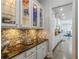 Hallway bar area with granite counters, wine rack, and glass front cabinetry at 4738 Ivy Ridge Se Dr, Atlanta, GA 30339