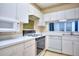 Bright kitchen showcasing white cabinetry, appliances, and countertops with range and hood at 240 Renaissance Pkwy # 116, Atlanta, GA 30308