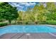 Backyard pool area with fencing, landscaping, and surrounding mature trees at 110 Cove Ln, Social Circle, GA 30025