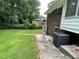 View of the backyard featuring a brick house with an AC unit, small patio, and grass at 2071 Carthage Rd, Tucker, GA 30084