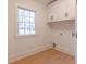 Bright laundry room with white cabinets and wood floors at 13130 Providence Rd, Milton, GA 30009