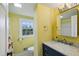 A bright bathroom features a blue vanity with marble countertop, yellow walls, and a window with natural light at 2956 Hogan Rd, East Point, GA 30344