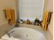 Relaxing bathroom with a jacuzzi tub, a window with blinds, and decorative items on the ledge at 5821 Saint Miles Dr, Buford, GA 30518