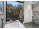 Luxurious bathroom with a soaking tub and marble shower, offering views of the wooded scenery at 2716 Ridgewood Nw Rd, Atlanta, GA 30327