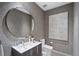 Stylish powder room featuring textured wallpaper, round mirror and modern vanity at 2716 Ridgewood Nw Rd, Atlanta, GA 30327