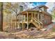 Green house exterior with deck, stairs, and stone pathway. Brick accents and wooded setting at 3830 High Point Cir, Cumming, GA 30041