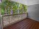 Cozy outdoor porch featuring wooden floors, paneled walls, and a lattice railing with a view of the surrounding trees at 504 Vicksburg Pl, Atlanta, GA 30350