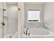 Bright bathroom features a soaking tub, shower with tile surround, and bronze fixtures at 1927 Streamlet Xing, Kennesaw, GA 30152