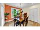 Bright dining room with wood table and chairs, an orange accent wall, and lots of plants at 1927 Streamlet Xing, Kennesaw, GA 30152