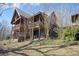 Exterior shot of a multi-story cabin with wooden decks, a sloped yard, and a wooded backdrop at 49 Holly Springs Ne Rd, White, GA 30184
