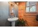 Rustic bathroom with wood paneled walls, pedestal sink, and decorative mirror at 49 Holly Springs Ne Rd, White, GA 30184