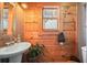 Rustic bathroom with wood paneled walls, pedestal sink, and decorative mirror at 49 Holly Springs Ne Rd, White, GA 30184