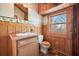 Bathroom featuring wood-paneled walls, decorative wallpaper border, single vanity, and warm wood accents at 49 Holly Springs Ne Rd, White, GA 30184