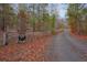 Rustic wooden entrance gate with a personalized sign, set amidst a scenic, tree-lined gravel driveway at 49 Holly Springs Ne Rd, White, GA 30184