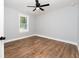 This bedroom features light gray walls, wood flooring, a ceiling fan and a window looking out onto a treed yard at 413 Cranfill Se Rd, Marietta, GA 30060