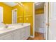 Bright yellow bathroom with double sink vanity, mirror and adjacent shower at 4311 Clairesbrook Ln, Acworth, GA 30101