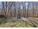 Wooded backyard featuring a swing set, slide, and mature trees at 6705 Brookline Ct, Cumming, GA 30040