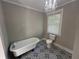 Bathroom with standalone tub, toilet, patterned tile flooring, and modern chandelier lighting at 31 N Broad N St, Porterdale, GA 30014