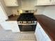 Close-up shot of a gas range with stainless steel finish and white cabinets on a black and white patterned floor at 31 N Broad N St, Porterdale, GA 30014