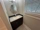 Vanity with dark wood, granite countertop, chrome faucet, and black and white tile floor at 31 N Broad N St, Porterdale, GA 30014