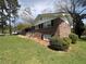 Charming brick home with well-manicured lawn, mature landscaping, and black shutters at 6595 Malvin Dr, Austell, GA 30168