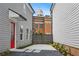 View of a backyard with a concrete patio, gravel accents, red door, and a domed building in the distance at 40 Spirea Way, Auburn, GA 30011