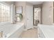 Bright bathroom featuring a soaking tub under a window and white vanity with framed mirror at 992 Bridgegate Ne Dr, Marietta, GA 30068