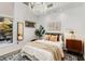 Bright bedroom with chandelier lighting, neutral decor, and a view of lush greenery outside the window at 130 Arizona Ne Ave # 104, Atlanta, GA 30307