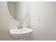 Elegant powder room with a pedestal sink and a round decorative mirror at 693 Sunstone Ln, Lawrenceville, GA 30043