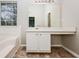 Bathroom vanity offering storage, and marble floors located next to a tub with window and natural light at 254 Cobblestone Ln, Mcdonough, GA 30252