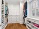 Spacious walk-in closet with custom shelving, cabinets, drawers, and a window allowing natural light at 6830 Vickery Creek Rd, Cumming, GA 30040