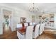 Elegant dining room with hardwood floors, white chairs, and a chandelier; built-in shelves add charm at 6830 Vickery Creek Rd, Cumming, GA 30040