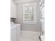 Functional laundry room with a washer and dryer, shelving, and a window with white shutters at 6830 Vickery Creek Rd, Cumming, GA 30040