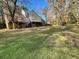 Large grassy backyard featuring a deck, stairs, and sunroom, surrounded by mature trees at 1200 Lakewood Ne Dr, Conyers, GA 30013