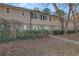 Traditional two-story townhouse with a tan and brick facade, small gated courtyard, and mature landscaping at 6940 Roswell Rd # E12, Atlanta, GA 30328