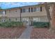 Traditional two-story townhouse with a tan and brick facade, small gated courtyard, and mature landscaping at 6940 Roswell Rd # E12, Atlanta, GA 30328