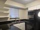 Kitchen features sleek black appliances, granite countertops, white cabinetry, and a double sink at 6940 Roswell Rd # E12, Atlanta, GA 30328