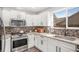 Modern kitchen featuring white cabinets, granite countertops, stainless steel appliances and tile backsplash at 1312 Buttercup Ct, Lawrenceville, GA 30044