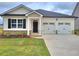 Charming one-story home with two-car garage, black door, and manicured lawn at 142 Oakchase Park Ln, Hampton, GA 30228