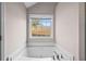 Bathtub in bathroom features a window and elegant fixtures at 90 Loudoun Dr, Covington, GA 30014