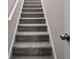 Carpeted staircase with white risers and handrail adds comfort and safety to the home's interior at 90 Loudoun Dr, Covington, GA 30014