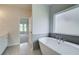 Bright bathroom featuring a soaking tub, grey tile, and vanity with grey tiling at 173 Haverling Pass, Hampton, GA 30228