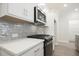 Updated kitchen featuring stainless steel microwave and range, white countertop, and gray tile backsplash at 909 Agate Ln, Lawrenceville, GA 30043