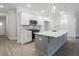 Bright kitchen features white cabinetry, gray backsplash, stainless steel appliances, and a gray kitchen island at 909 Agate Ln, Lawrenceville, GA 30043