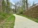A smooth concrete path winding through a wooded area with a retaining wall at 1995 Catnap Ct, Chamblee, GA 30341