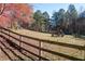 Expansive backyard with mature trees and fall colors, featuring a wooden fence and play set at 355 Clark Creek Pass, Acworth, GA 30102