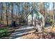 Exterior of the outbuilding with stone and barn door detail plus baseball batting cage and stack of logs at 355 Clark Creek Pass, Acworth, GA 30102